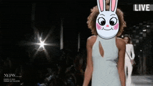 a woman wearing a bunny mask walks down a runway at a nyfw fashion show