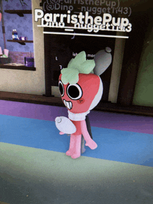 a stuffed strawberry is standing in front of a sign that says parrish the pup