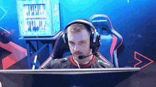 a man wearing headphones and a shirt that says syner sits in front of a computer screen
