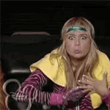a woman wearing a yellow vest and pink gloves is making a funny face while sitting in a car .