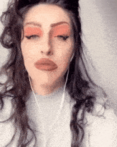 a woman wearing headphones and red eye shadow is making a funny face
