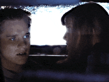 a man and a woman are looking at each other in a dark room