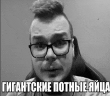 a man wearing glasses and a mohawk is sitting in a chair with a caption in russian .