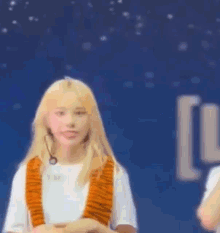 a blonde girl wearing a tiger scarf and a white shirt is standing on a stage .