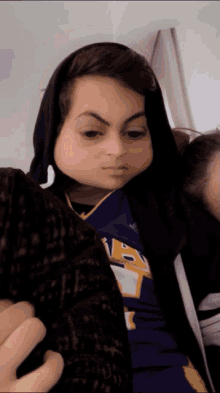 a person wearing a hoodie and a lakers jersey making a face