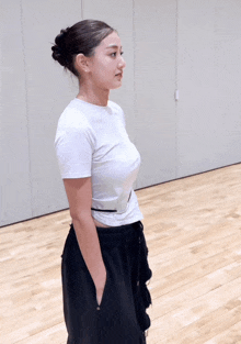 a woman in a white t-shirt and black shorts is standing with her hands in her pockets