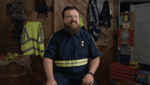 a man with a beard is sitting in front of a sign that says you guys do n't know either