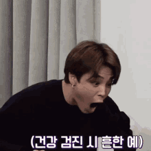a close up of a person making a funny face with korean writing on the bottom .