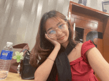 a bottle of aquafina water sits on a table next to a girl wearing glasses