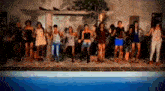 a group of people are dancing in front of a swimming pool .
