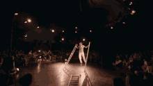 a man stands on a ladder in front of a crowd of people