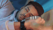 a man is sleeping on a bed with his eyes closed and a watch on his wrist
