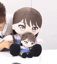 a woman is holding two stuffed dolls one of which is a girl with purple eyes