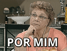 an older woman wearing glasses and a pearl necklace is sitting at a table with the words por mim above her