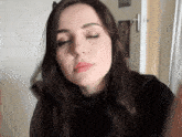 a woman with her eyes closed is wearing a black top