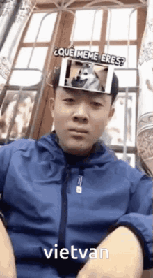 a man in a blue jacket has a picture of a dog on his head and the word vietvan below it