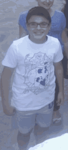 a boy wearing glasses and a white shirt with a shield on the front