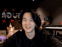a young man is smiling while sitting at a table in front of a keyboard .