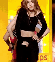 a woman in a black crop top and black skirt is standing on a stage .