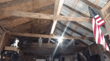 an american flag is hanging from the ceiling of a wooden building