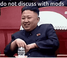 a man in a suit is sitting in a stadium with the words do not discuss with mods behind him