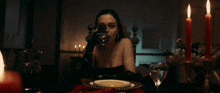 a woman sits at a table with a plate and candles