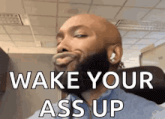 a bald man with a beard is making a funny face while wearing headphones and saying wake your ass up .