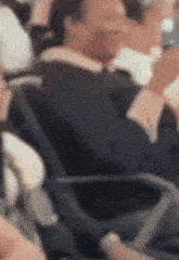 a blurry picture of a man in a suit and tie sitting in a chair