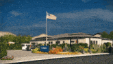 an american flag is flying in front of a building with a sign that says ' the gardens ' on it