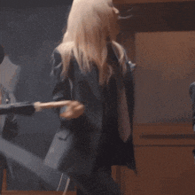 a woman in a suit and tie is dancing with a smiley face in the background