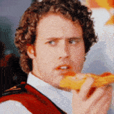 a man with curly hair is holding a slice of pizza in his hand