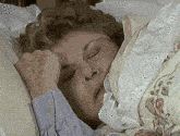 an older woman is sleeping in a bed with a floral comforter