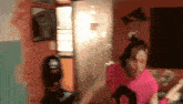 a woman in a pink shirt is dancing in a room with a man in a black hat behind her