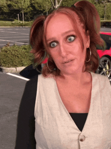 a woman with pigtails is making a funny face in front of a red car