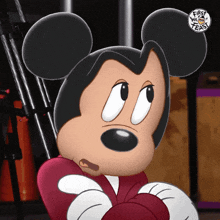 a close up of a mickey mouse with a first we teach logo in the corner