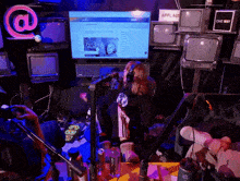a woman speaking into a microphone in front of a screen that says applaud on it