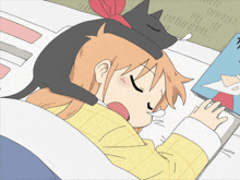a girl with a cat on her head sleeping next to a book