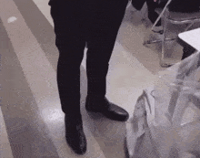 a person wearing black shoes is standing on a floor