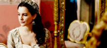 a woman with a tiara on her head looks at herself in a mirror
