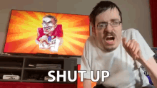 a man sitting in front of a television with the words shut up written on it