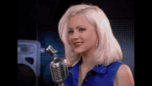 a woman is singing into a microphone in a blue shirt .