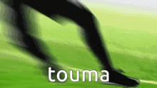 a blurry picture of a person running on a grassy field with the word touma written on the bottom .