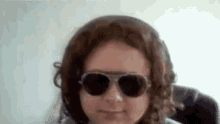 a young girl wearing sunglasses and headphones is smiling for the camera .