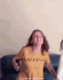 a woman wearing a yellow shirt that says ntf is dancing