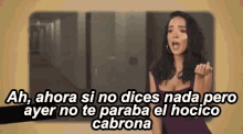 a woman in a purple dress is making a funny face while talking in spanish