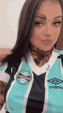 a woman with a tattoo on her face is wearing a jersey that says umbro on it