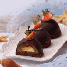 three chocolate desserts with strawberries on top on a plate