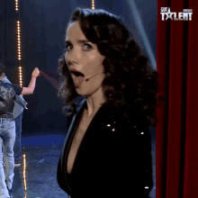 a woman with her tongue out is on a stage in front of a red curtain with the word talent on it