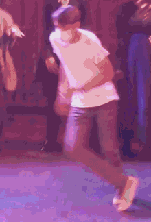 a man in a white shirt is dancing in front of a purple background