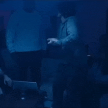 a group of people are dancing in a dark room with a laptop .